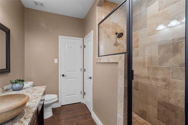 bathroom featuring hardwood / wood-style flooring, vanity, toilet, and an enclosed shower