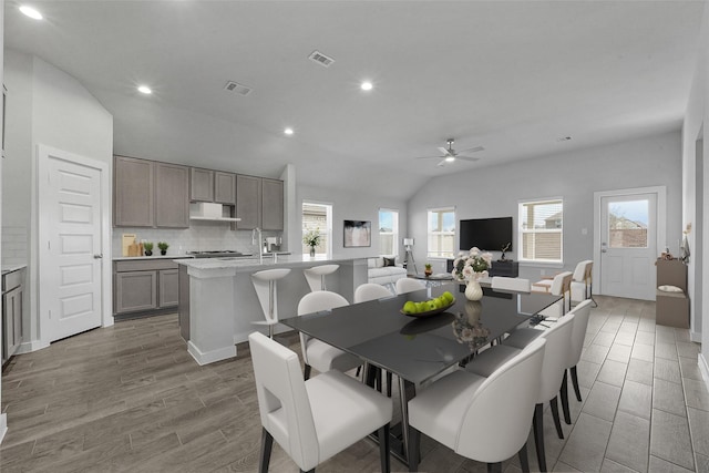 dining space featuring ceiling fan, sink, and vaulted ceiling