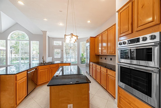 kitchen with dark stone countertops, a center island, kitchen peninsula, sink, and stainless steel appliances