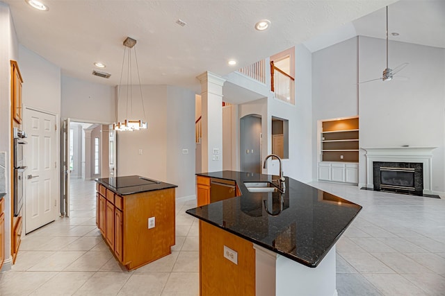 kitchen with pendant lighting, a center island with sink, sink, built in features, and a high end fireplace