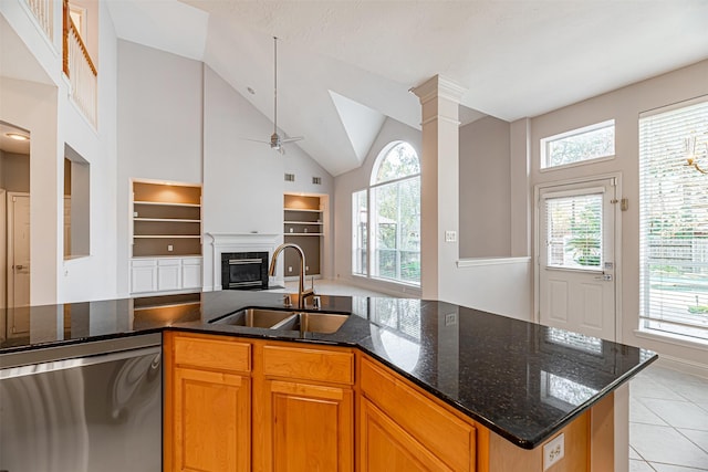 kitchen with stainless steel dishwasher, dark stone countertops, sink, ceiling fan, and light tile patterned floors