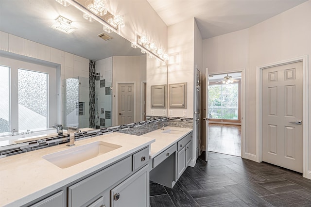 bathroom with ceiling fan, vanity, decorative backsplash, and a tile shower