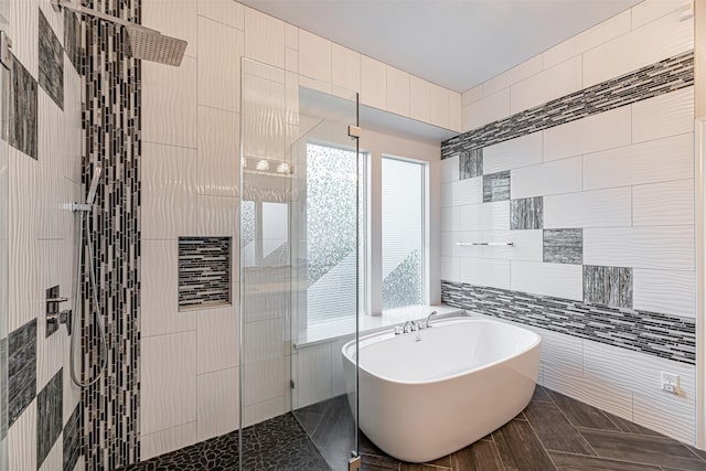 bathroom featuring plus walk in shower and tile walls