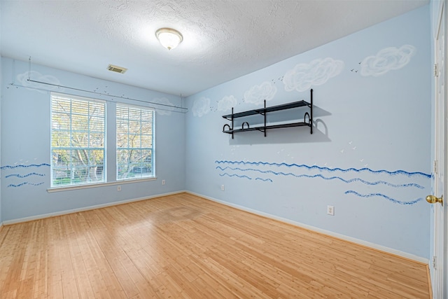 empty room with wood-type flooring and a textured ceiling