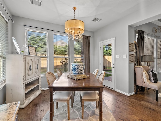 dining area featuring a healthy amount of sunlight, dark wood-type flooring, and an inviting chandelier