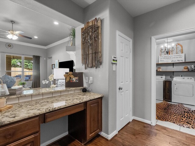 kitchen with ornamental molding, ceiling fan with notable chandelier, dark wood-type flooring, and washing machine and clothes dryer