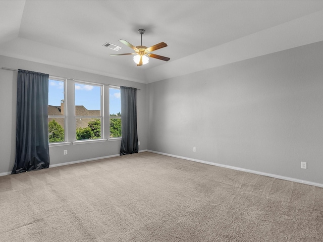 carpeted spare room with a tray ceiling, ceiling fan, and vaulted ceiling