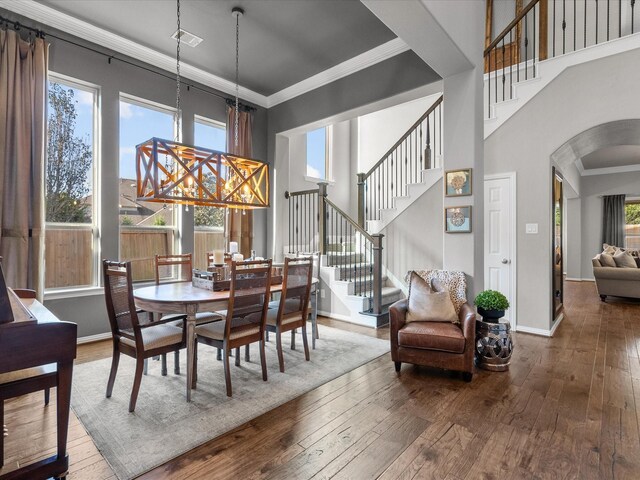 dining room featuring a healthy amount of sunlight, wood-type flooring, and crown molding