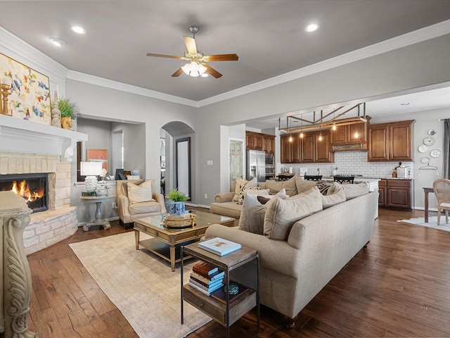 living room featuring a fireplace, dark hardwood / wood-style floors, crown molding, and ceiling fan