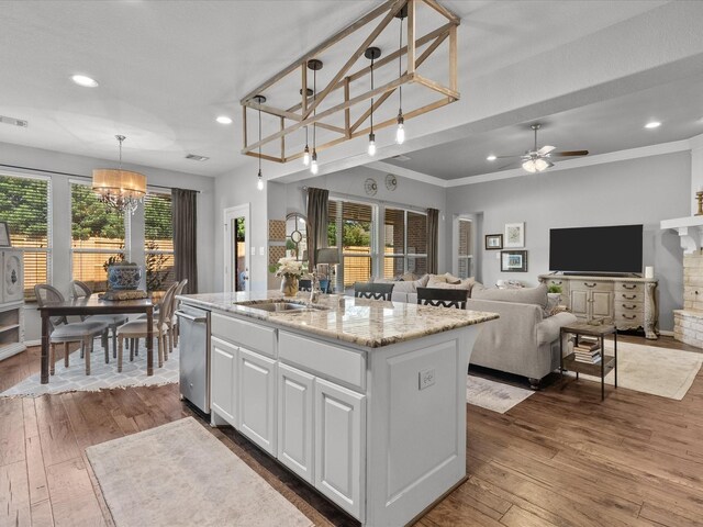 kitchen with a kitchen island with sink, dark wood-type flooring, white cabinets, ceiling fan with notable chandelier, and decorative light fixtures