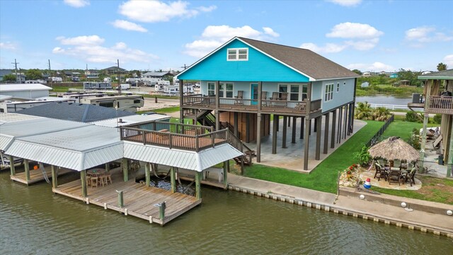 rear view of house with a deck with water view and a patio