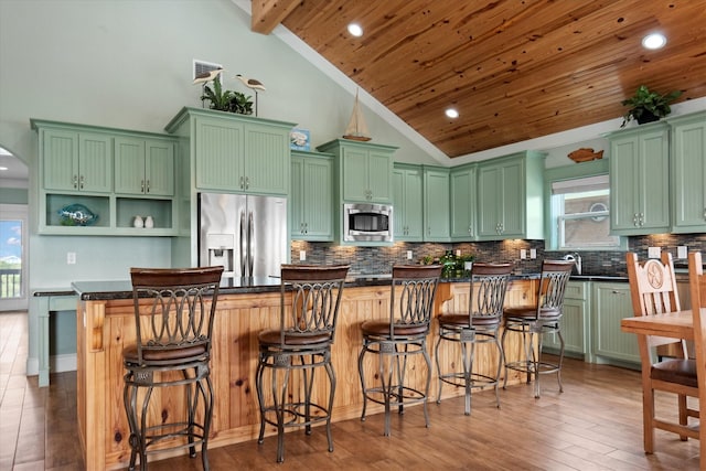 kitchen featuring a center island, wooden ceiling, a kitchen bar, appliances with stainless steel finishes, and green cabinetry