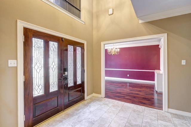 tiled foyer entrance featuring french doors, ornamental molding, and a chandelier