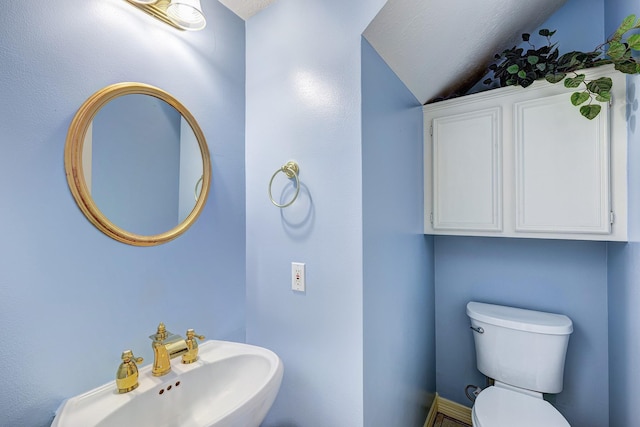 bathroom with vaulted ceiling, toilet, and sink