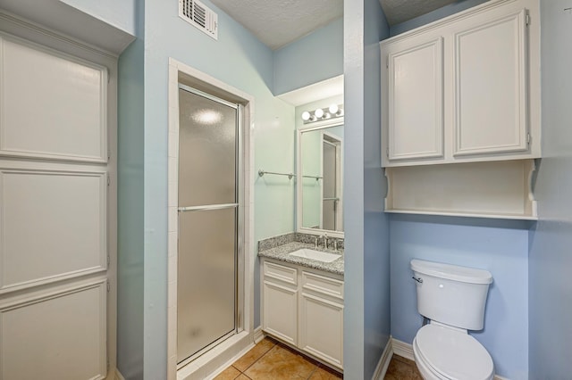 bathroom with vanity, tile patterned floors, toilet, a textured ceiling, and an enclosed shower