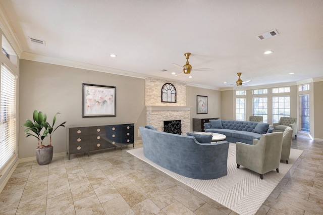 living room with a stone fireplace, ceiling fan, plenty of natural light, and crown molding