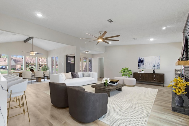 living room with lofted ceiling with beams, a fireplace, ceiling fan, and light hardwood / wood-style floors