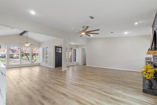 unfurnished living room featuring a fireplace, lofted ceiling with beams, light hardwood / wood-style floors, and a wealth of natural light