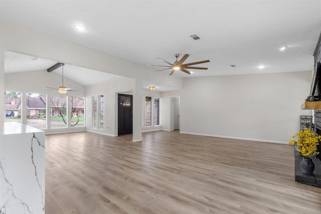 unfurnished living room featuring lofted ceiling with beams, a fireplace, and light hardwood / wood-style flooring