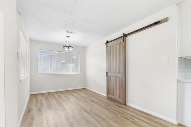 spare room featuring a barn door and light hardwood / wood-style floors