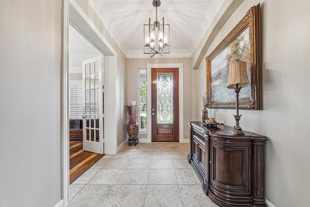 foyer featuring light tile patterned floors, an inviting chandelier, and crown molding