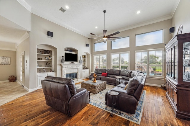 living room with ornamental molding, a textured ceiling, ceiling fan, hardwood / wood-style flooring, and built in features