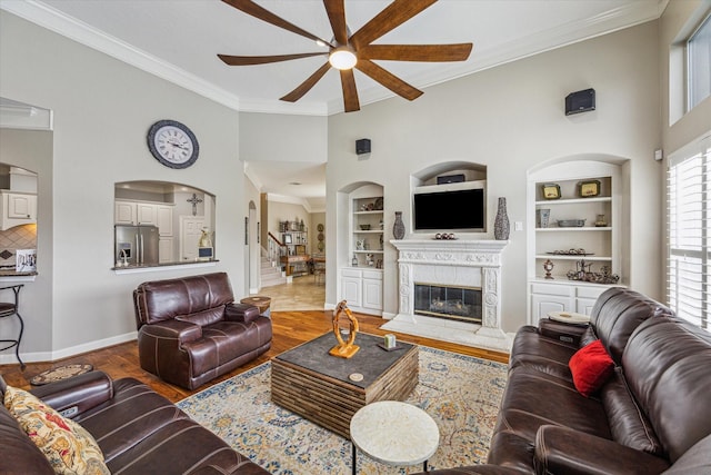 living room featuring built in shelves, ceiling fan, a fireplace, and hardwood / wood-style flooring