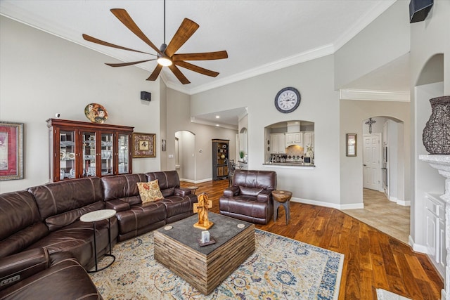 living room with hardwood / wood-style floors, ceiling fan, crown molding, and a high ceiling