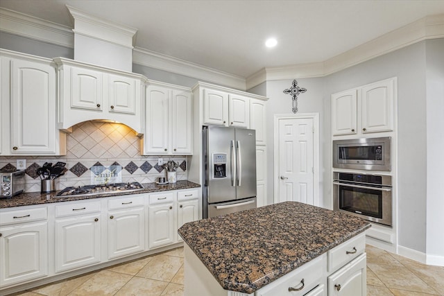 kitchen with white cabinets, a center island, stainless steel appliances, and tasteful backsplash