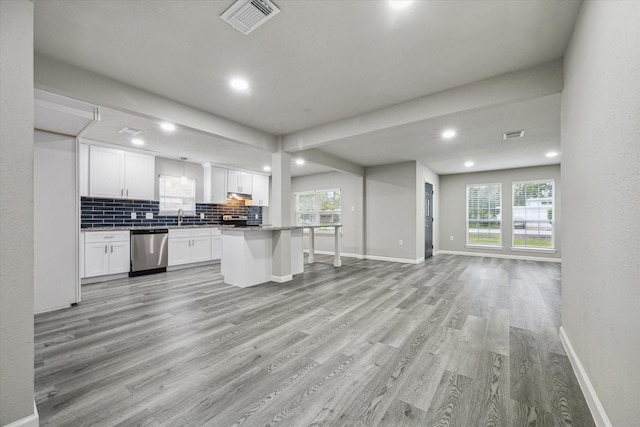 kitchen with light wood-type flooring, backsplash, stainless steel appliances, a center island, and white cabinetry