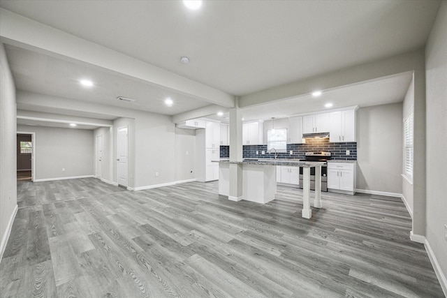 kitchen featuring light stone countertops, stainless steel range with electric stovetop, sink, white cabinets, and a center island