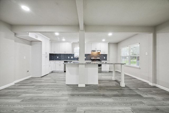 kitchen with stainless steel range with electric stovetop, white cabinets, light stone countertops, light hardwood / wood-style floors, and a kitchen island