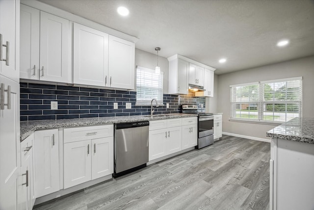 kitchen featuring appliances with stainless steel finishes, sink, pendant lighting, white cabinets, and light hardwood / wood-style floors