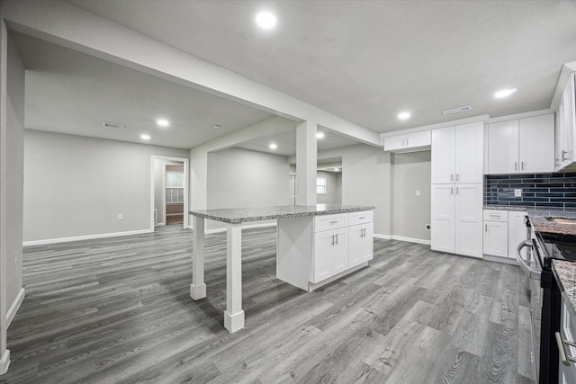 kitchen with a kitchen breakfast bar, a center island, white cabinetry, and light stone counters