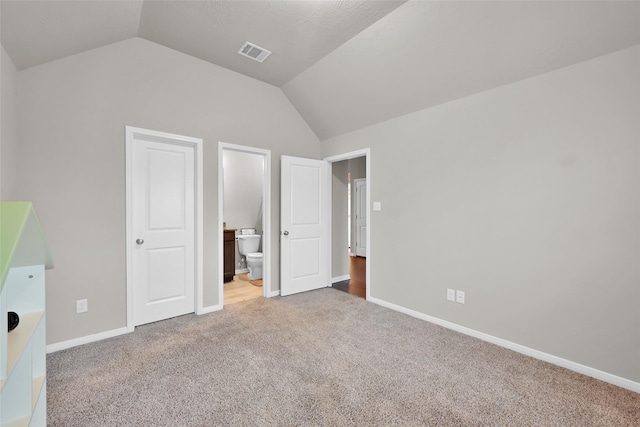 unfurnished bedroom featuring carpet flooring, lofted ceiling, and ensuite bath