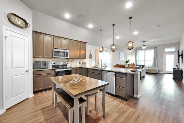 kitchen featuring pendant lighting, sink, ceiling fan, light stone counters, and stainless steel appliances