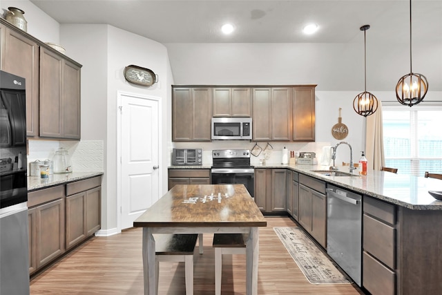 kitchen featuring sink, tasteful backsplash, decorative light fixtures, light stone counters, and stainless steel appliances