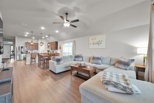 living room with light hardwood / wood-style floors, vaulted ceiling, and ceiling fan