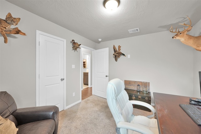 carpeted home office featuring a textured ceiling