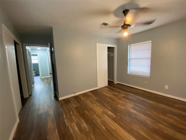 unfurnished bedroom featuring multiple windows, ceiling fan, a closet, and dark wood-type flooring