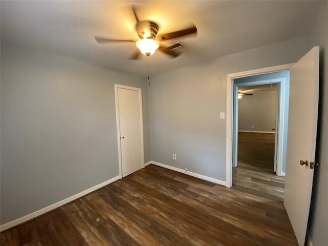 unfurnished bedroom with ceiling fan, dark hardwood / wood-style floors, and a closet