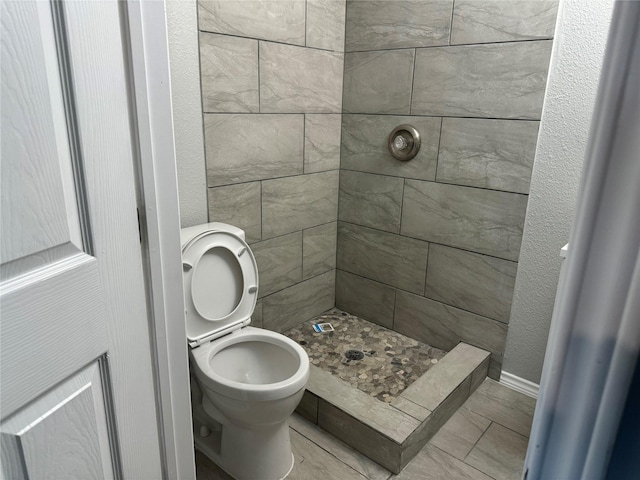 bathroom with toilet and tiled shower