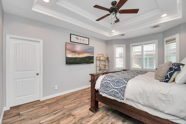 bedroom featuring a raised ceiling, ceiling fan, hardwood / wood-style floors, and ornamental molding