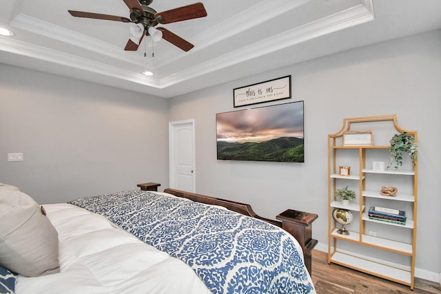 bedroom with a raised ceiling, ceiling fan, crown molding, and hardwood / wood-style flooring