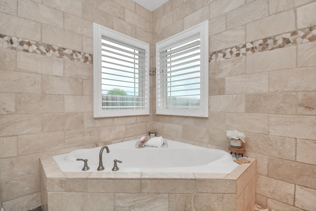 bathroom with tiled tub and tile walls