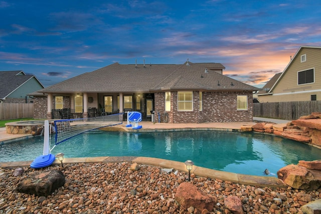 pool at dusk with an in ground hot tub, a patio, and pool water feature