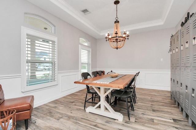 dining room featuring a tray ceiling, light hardwood / wood-style flooring, and an inviting chandelier