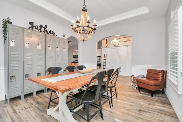 dining area featuring a chandelier, light wood-type flooring, ornamental molding, and a tray ceiling