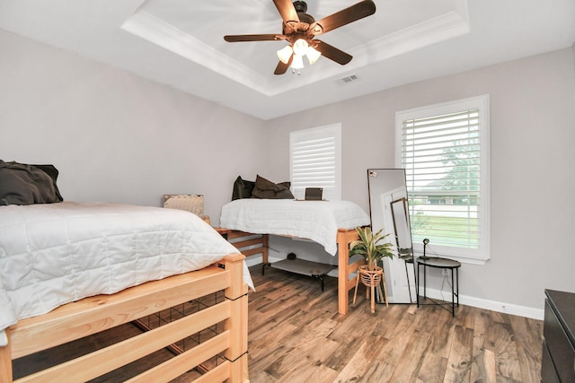 bedroom featuring wood-type flooring, a tray ceiling, ceiling fan, and ornamental molding