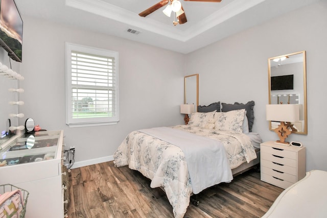 bedroom featuring ceiling fan, dark hardwood / wood-style floors, a raised ceiling, and ornamental molding